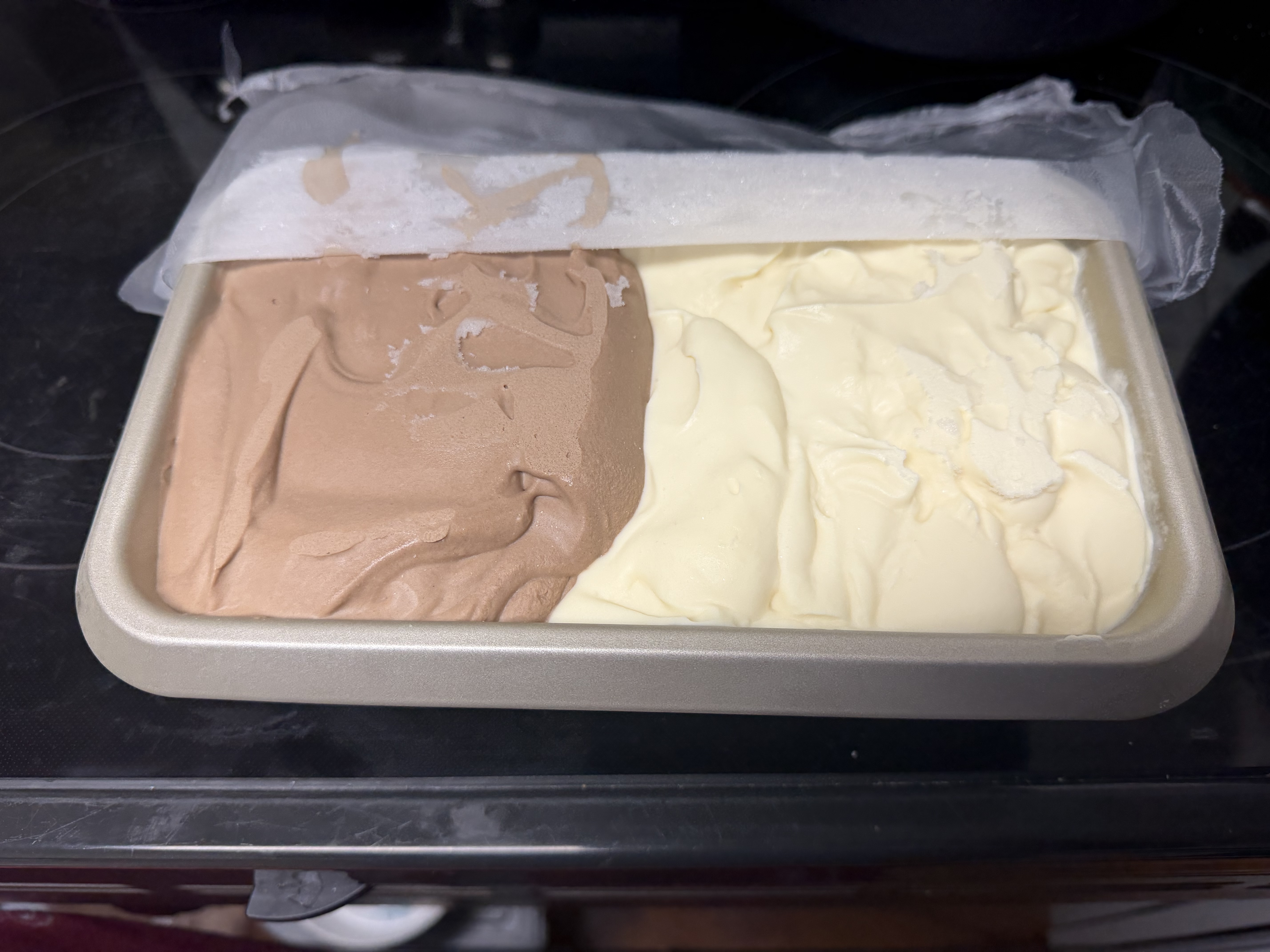 Vanilla and chocolate ice cream side by side in a loaf pan in the freezer
